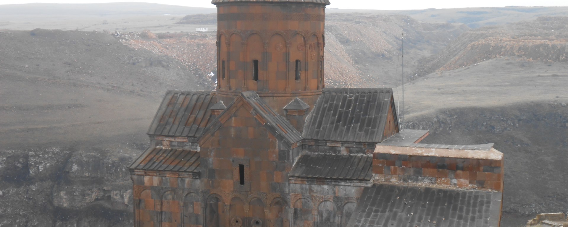 Armenian-style church topped by rounded cone atop cliffside in Ani ancient city