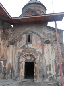 Entrance to old church with paintings of Christ visible above arched doorways