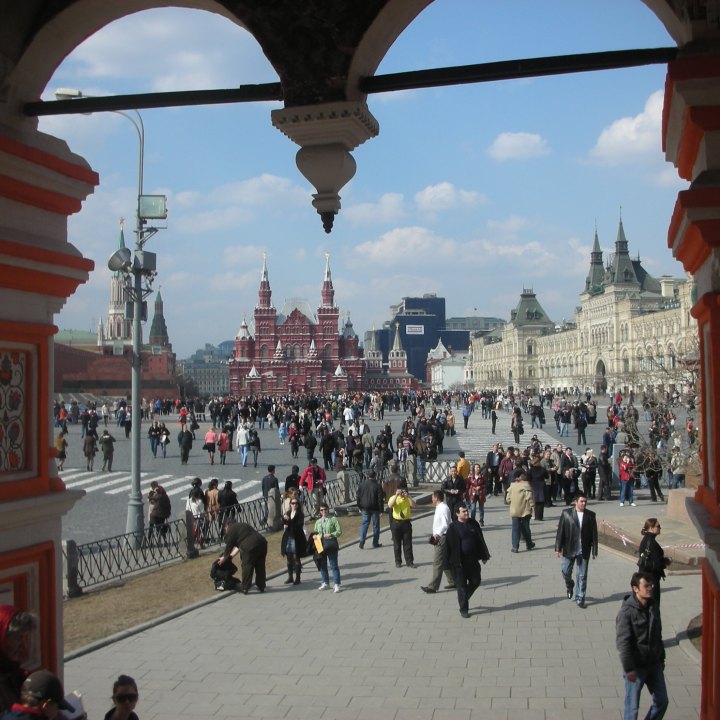 Moscow's Red Square seen from inside church arches with big red and white buildings in background