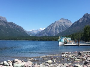 Classic boat on mountain lake framed by mountains on clear day in Glacier Park