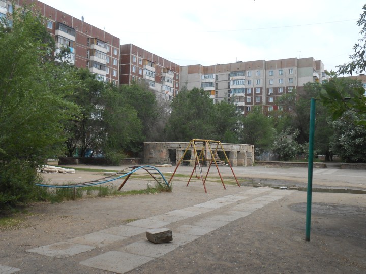 Soviet-style apartment blocks frame a children's playground