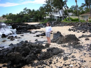 woman on beach in Hawaii with black lava rocks and palm trees