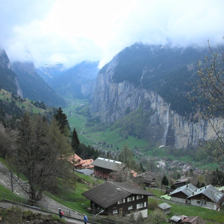 steep valley with gray cliffs and waterfalls with Swiss chalets in foreground