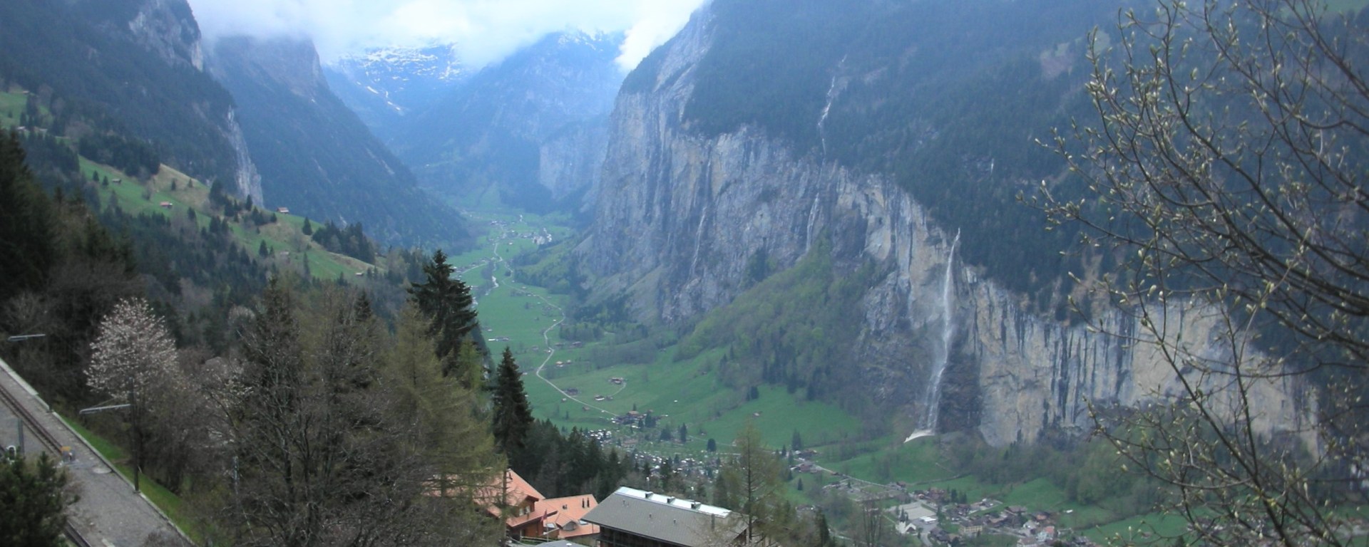 steep valley with gray cliffs and waterfalls with Swiss chalets in foreground