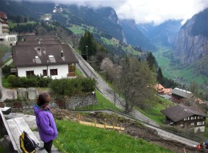 woman gazing downhill at steep valley with chalet houses