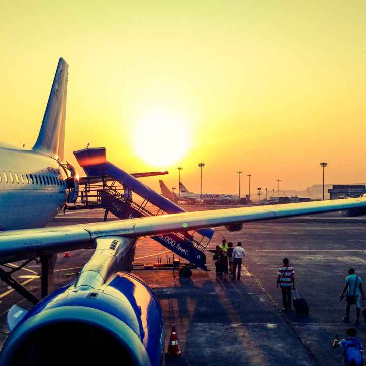 golden sunrise behind jet airplane with passengers boarding a stairway