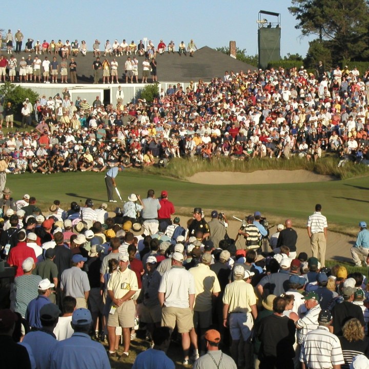 golfer putts on last green of US Open tournament with crowds encircling
