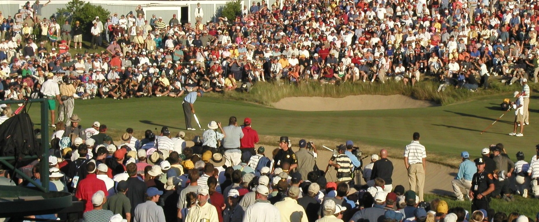 golfer putts on last green of US Open tournament with crowds encircling