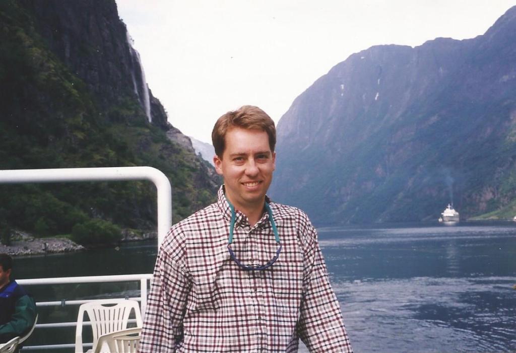 man on ferry in a Norwegian fjord with steep cliffs in background